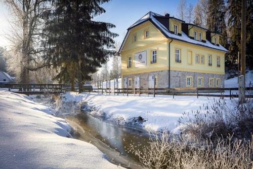 阿德尔什帕赫Skalní Mlýn Adršpach的河边雪中的一个黄色房子