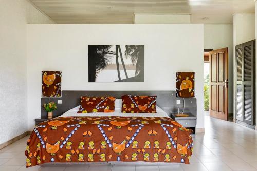阿西尼Hotel Coucoue Lodge的一间卧室配有一张带橙色枕头的大床