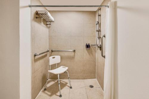 瓜达拉哈拉瓜达拉哈拉博览会嘉年华酒店的浴室内配有带白色椅子的淋浴