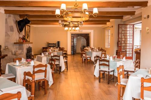 Los Baños del IncaHOTEL & SPA LAGUNA SECA的餐厅配有白色的桌椅和吊灯