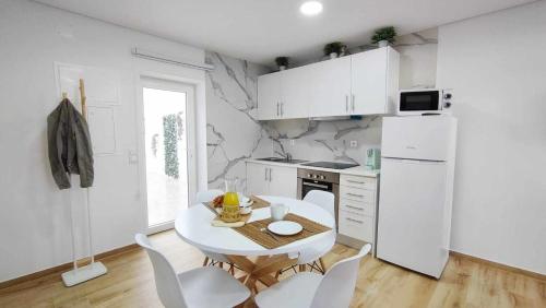 拉夫拉Casa de Praia Daniel的白色的厨房配有桌子和白色家电