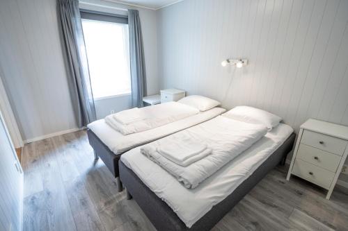 艾于兰Skaimsberg Holiday Apartments的一间卧室设有两张带白色床单的床和窗户。
