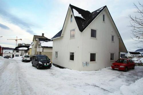 哈尔斯塔Sentral leilighet med 3 soverom 2etg的雪中带黑色屋顶的白色房子