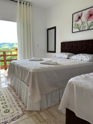林多亚Chácara Jerusalém的一间卧室设有两张带白色床单的床和窗户。