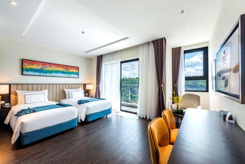 下龙湾Best Western Premier Sapphire Ha Long的酒店客房带两张床和一张桌子以及椅子。