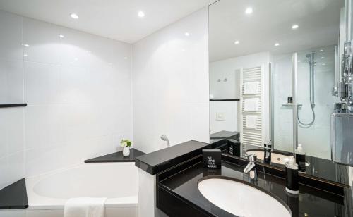慕尼黑慕尼黑瑞拉诺酒店的白色的浴室设有水槽和浴缸。