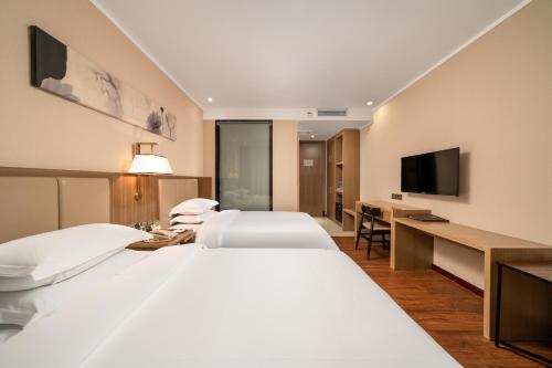 广州广州柏逸酒店的酒店客房设有两张床和一台平面电视。