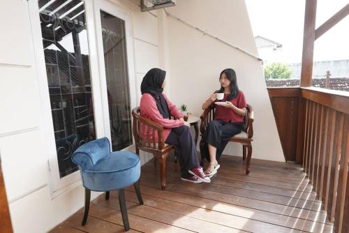 TimuranINEZ Homestay Prawirotaman Yogya的坐在房子门廊上的两名妇女