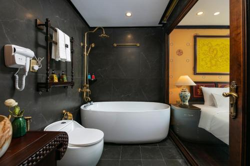 下龙湾Nostalgia Halong Cruise的带浴缸的浴室和卧室