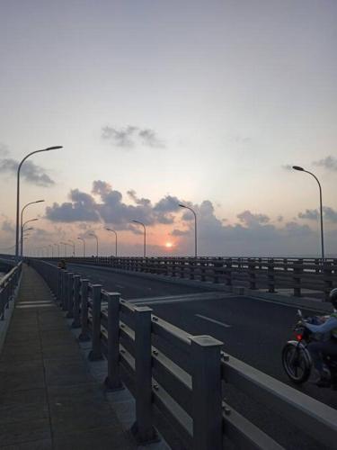 马累finifenma stay please book if you already in Maldives的一辆摩托车在高速公路上,在后面是日落