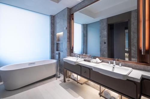 无锡无锡梁鸿湿地丽笙度假酒店的浴室配有2个盥洗盆、浴缸和大镜子