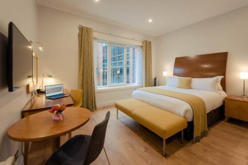 都柏林PREMIER SUITES Dublin, Leeson Street的配有一张床、一张桌子和一张桌子的酒店客房