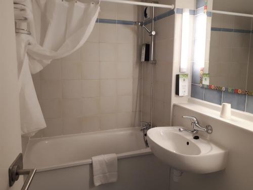 布鲁瓦Kyriad Blois Nord的浴室配有水槽、浴缸和水槽