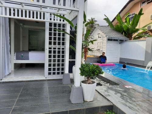 关丹Beit Azzahra Private Pool Villa at Pantai Batu Hitam的坐在房子旁边的游泳池旁的人