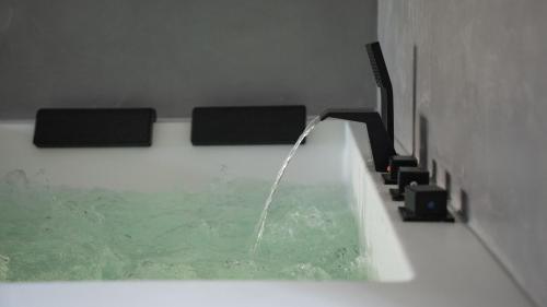 佩皮尼昂Ennéa - Jacuzzi & Luxury Suites的浴缸内有水流