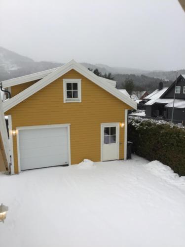 沃斯Sandvik Garasjeloft的雪上设有白色车库门的黄色房子