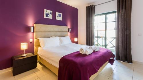 Central Albufeira Great Location的一间卧室配有一张紫色墙壁的床