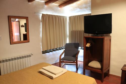 蒂尔卡拉Hotel Punta Corral的一间卧室配有一张床、一台电视和一把椅子