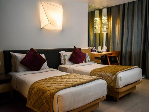 科泽科德Nexstay Asma Tower的酒店客房设有两张床和一张桌子。