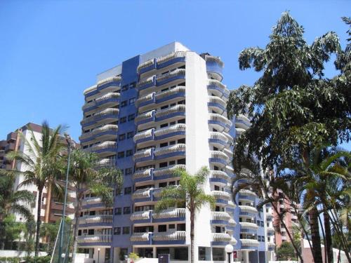 圣劳伦斯海滨Riviera Modulo 6 - 150 metros da praia - ATENÇÃO Piscina em reforma的一座高大的白色建筑,前面有棕榈树