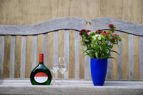 伊普霍芬Biobausewein WEIN HOTEL LEBEN的一瓶葡萄酒和一张长凳上的花瓶