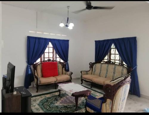 Kampong Parit TengahD'Aman Guesthouse Pontian的客厅配有2把椅子和蓝色窗帘