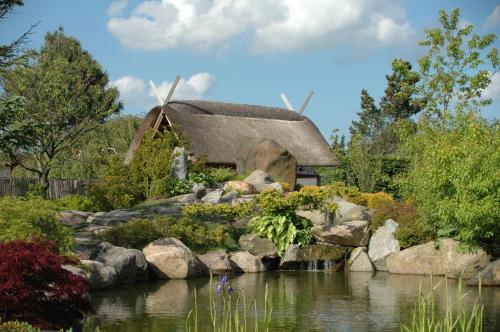 奥胡斯First Camp Aarhus - Jylland的茅草屋顶的房子,花园中设有一个池塘