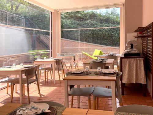 乌尔比诺天堂住宿加早餐旅馆的餐厅设有桌椅和大窗户。