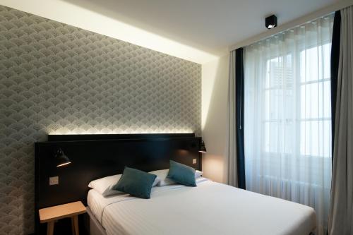 日内瓦派克斯酒店的一间卧室配有一张带大窗户的床和白色床罩