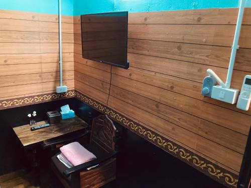 梭桃邑โรงแรมคุ้มเดช - KoomDech Hotel的一间设有木墙和电视的客房