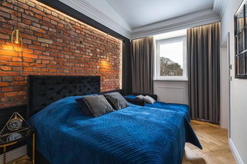 格但斯克Oliwa Am Calsberg 5a的一间卧室配有一张蓝色的床和砖墙