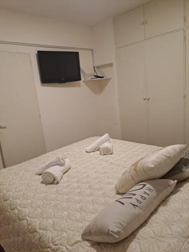 布宜诺斯艾利斯Obelisco的一间卧室配有带两个枕头的床和电视