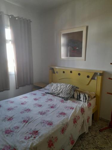 瓜拉派瑞Ap 300m praia do morro的一间卧室配有一张带花卉床罩的床