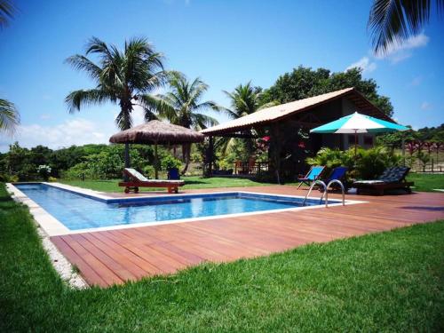 巴拉多库努Villa Angelim - Natureza e Conforto Barra do Cunhaú的庭院内带椅子和遮阳伞的游泳池