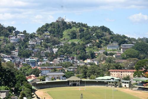 康提Cozy Homestay Kandy的享有城市美景,在田野上设有一个网球场