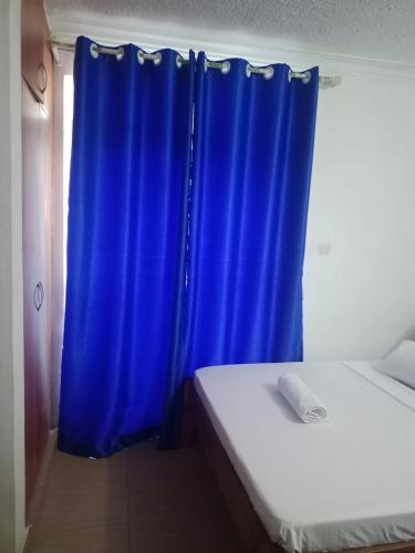蒙巴萨Mash Studio Apartment的卧室配有蓝色窗帘,毗邻一张床