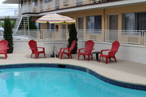 梅德福索瓦纳酒店的一个带椅子和桌子的游泳池以及一把遮阳伞