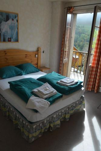 拉格拉沃HOTEL DES ALPES - SKIERS LODGE的一间卧室配有一张带绿色床单的床和一扇窗户。