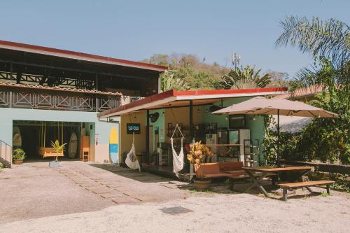 圣塔特蕾莎海滩Habitat Surf Glamp的一座带野餐桌和遮阳伞的建筑