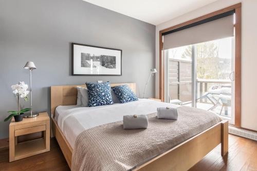 苏必利尔湖Suites sur Lac Superieur-Mont-Tremblant的一间卧室配有一张带蓝色枕头的床和一个阳台
