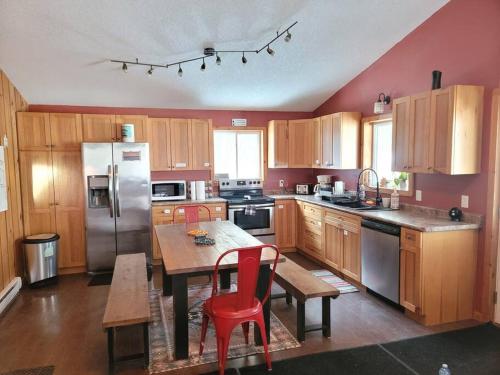 GilmourMarshmallow home的厨房配有木制橱柜和一张带红色椅子的桌子。