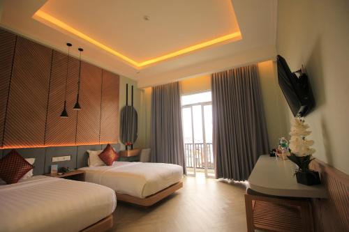 PadangluarMuara Hotel Bukittinggi的酒店客房设有两张床和电视。