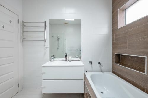 悉尼Elegant Federation Home Near The Airport的白色的浴室设有浴缸、水槽和浴缸。