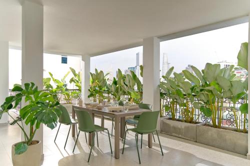 胡志明市M Village Nguyễn Du的用餐室配有绿色椅子和植物桌子