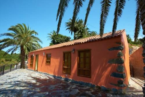 阿古洛Casa Rural Las Avestruces的一座种植了棕榈树的橘子小房子