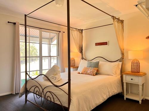 Rosebrook卡达尔小屋的一间卧室设有四柱床和窗户。