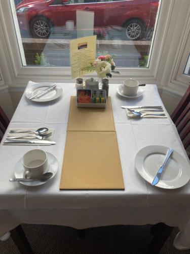 惠特比Ellies Guest House的一张带盘子和餐具的白色桌子