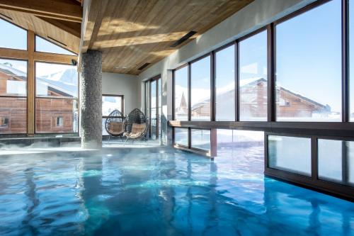 拉普拉涅CGH Résidences & Spas White Pearl Lodge的一座拥有蓝色海水和窗户的室内游泳池