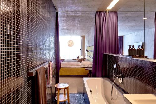 巴塞尔游牧设计与生活方式酒店的带浴缸的浴室和1间带1张床的卧室
