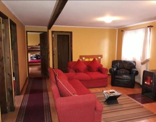 FreireHosteria y Cabañas Rucantu的客厅配有红色的沙发和椅子